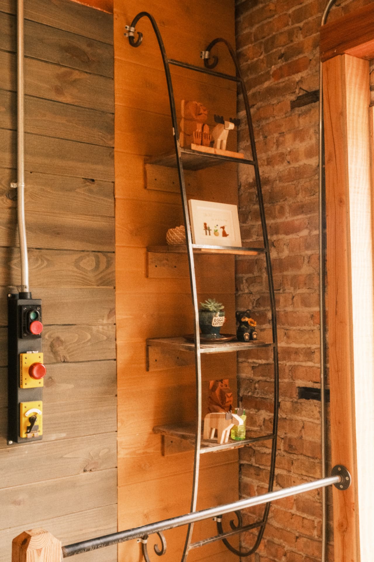 A tall display shelf against wood paneling and original brick inside DSCO Coffee