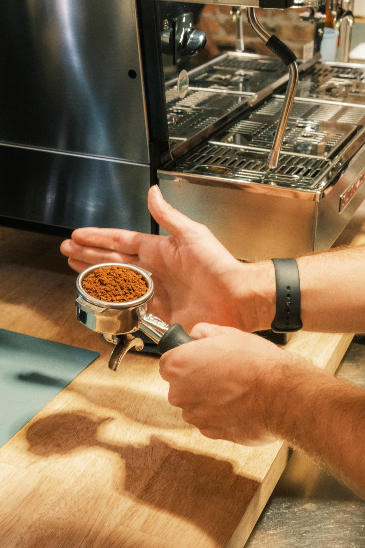 A barista leveling freshly ground espresso in a portafilter