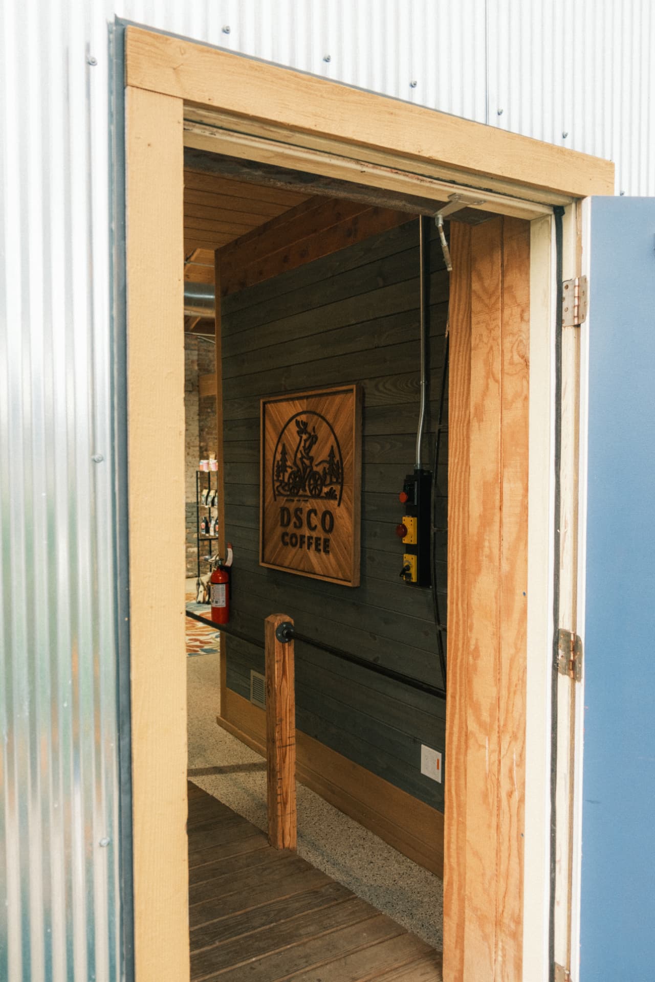 The open side entrance framing the handcrafted DSCO Coffee wooden sign