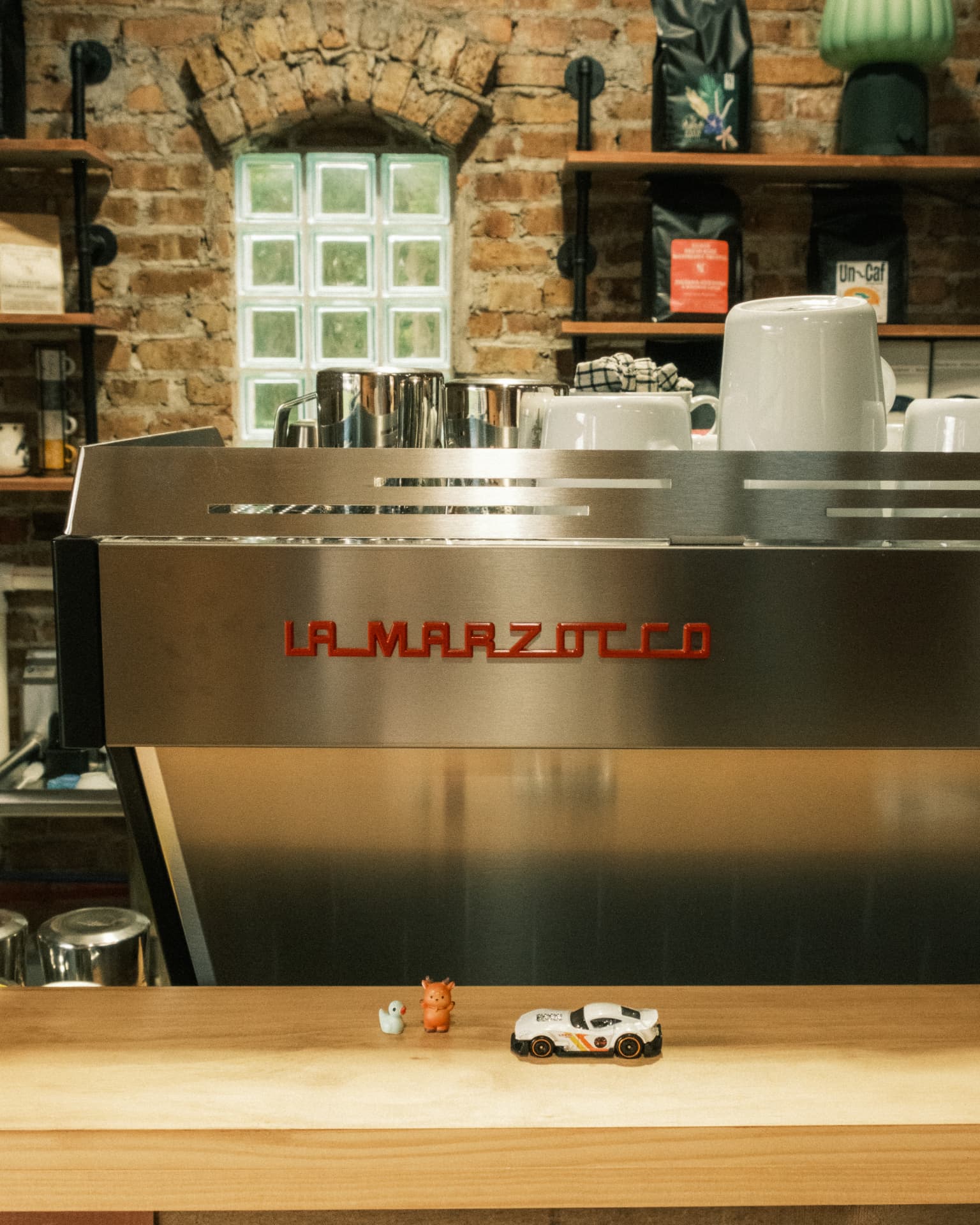 La Marzocco espresso machine with small toys resting on the wooden counter