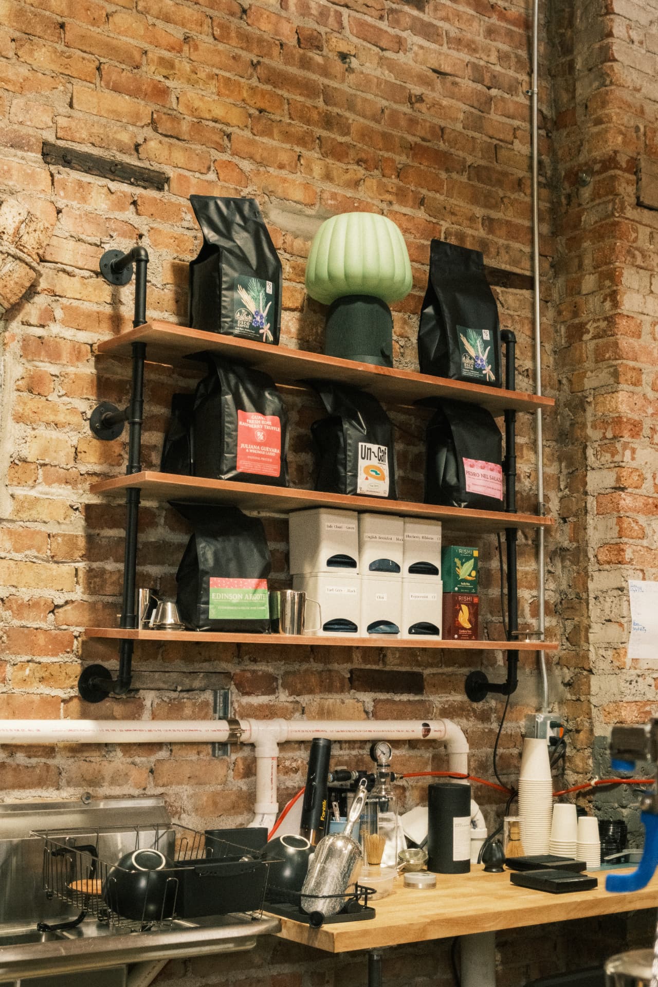Reprise Roasters coffee bags displayed on pipe shelves against the original brick wall
