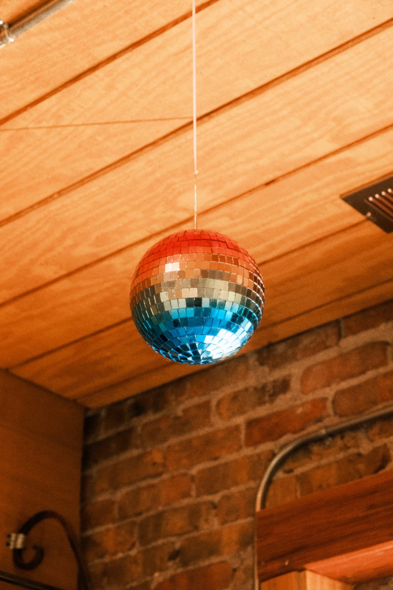A colorful disco ball hanging from the wood ceiling inside DSCO Coffee