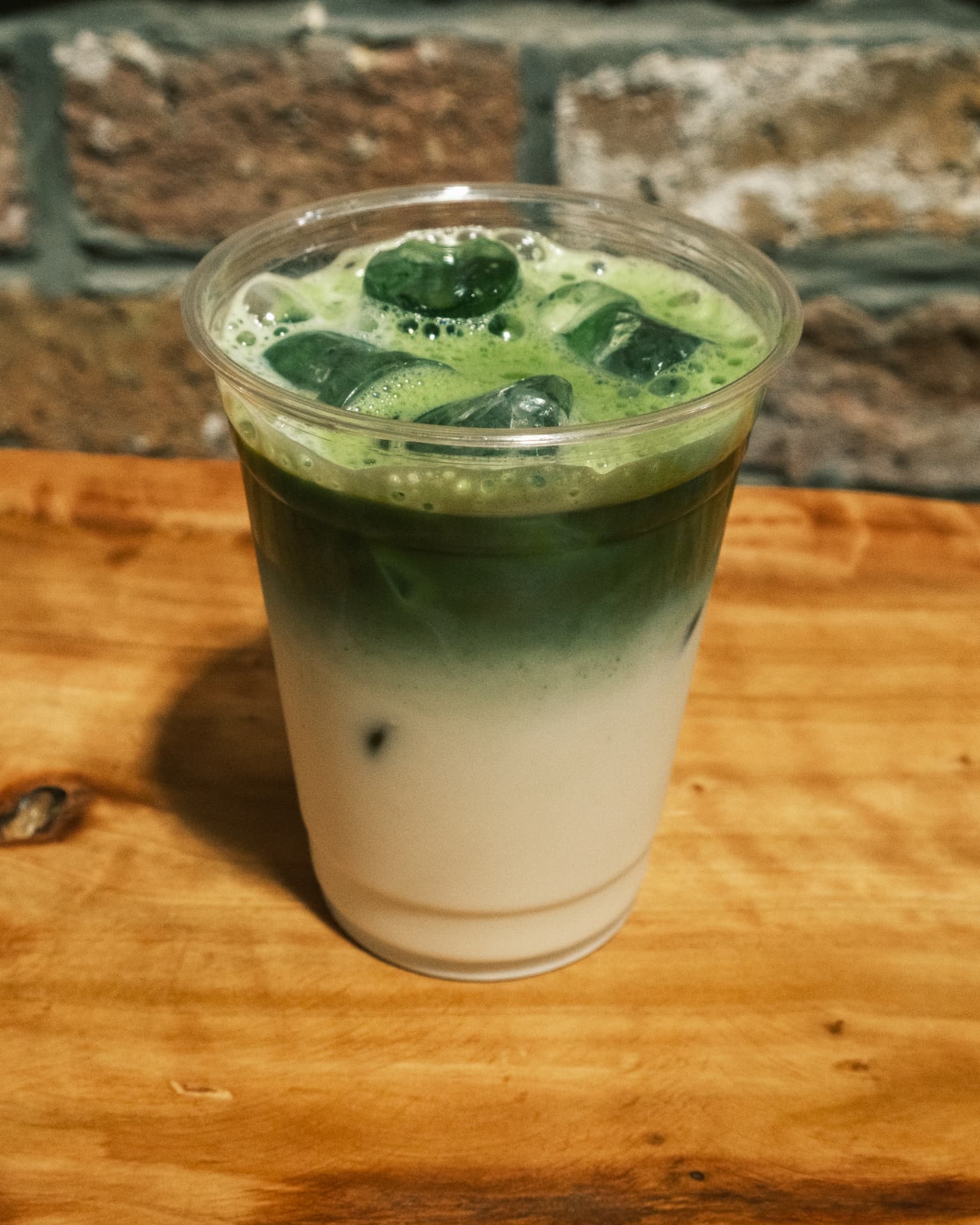 An iced matcha latte in a tall glass with a DSCO Coffee logo on the glass